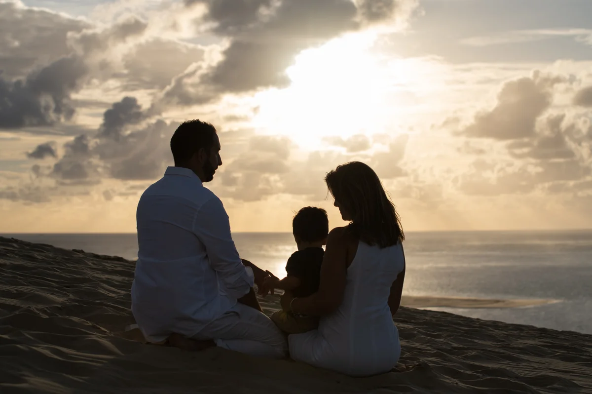 Séance portrait, silhouette d'une famille sur une dune au coucher du soleil